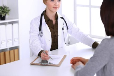 Hastane muayenehanesindeki genç kadın doktor ve hasta. Haki renkli terapist bluzu iyi görünüyor. Tıp, sağlık ve doktor randevu kavramı