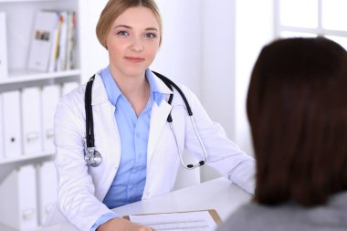 Hastane muayenehanesindeki genç kadın doktor ve hasta. Terapistin mavi renkli bluzu iyi görünüyor. Tıp ve sağlık hizmetleri kavramı
