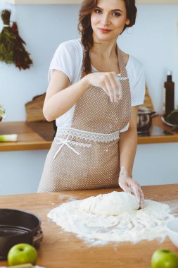 Genç esmer kadın mutfakta pizza ya da el yapımı makarna pişiriyor. Ev hanımı ahşap masada hamur hazırlıyor. Diyet, gıda ve sağlık konsepti