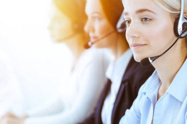 Güneşli ofiste çalışan bir grup farklı telefon operatörü. Kulaklıklı yakışıklı iş kadını müşterilere danışıyor. Çağrı merkezi ve iş adamları kavramı