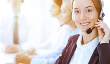 Güneşli ofiste çalışan bir grup farklı telefon operatörü. Kulaklıklı yakışıklı iş kadını müşterilere danışıyor. Çağrı merkezi ve iş adamları kavramı