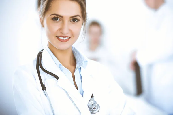 Doctora sonriendo en el fondo con paciente en la cama y dos doctores — Foto de Stock