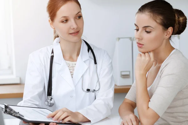 Médecin et patient assis et discutant des résultats de l'examen de santé dans une clinique ensoleillée — Photo