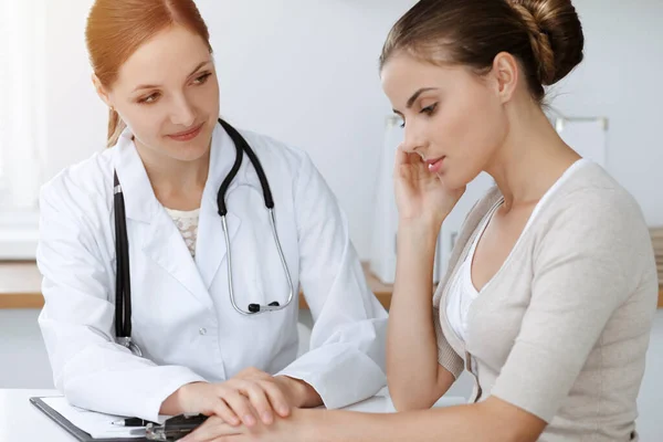 Médecin et patient assis et discutant des résultats de l'examen de santé dans une clinique ensoleillée — Photo