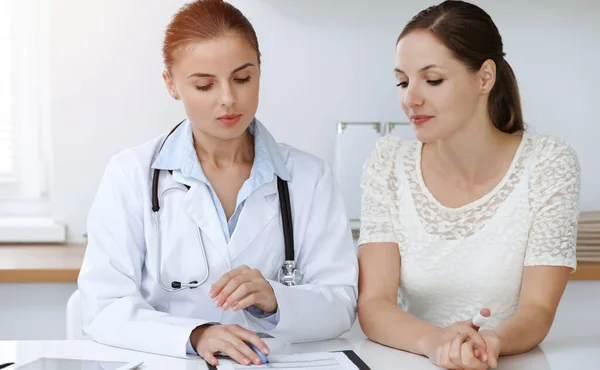 Doctor y paciente sentados en el escritorio. El médico o terapeuta hace un diagnóstico. Concepto de atención de salud, medicina y servicio al paciente — Foto de Stock