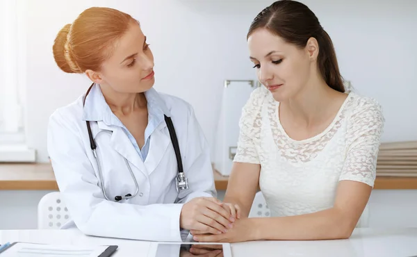 여자 의사가 책상에 앉아 있는 여성 환자를 안심시키고 있어. 의학적 개념 — 스톡 사진