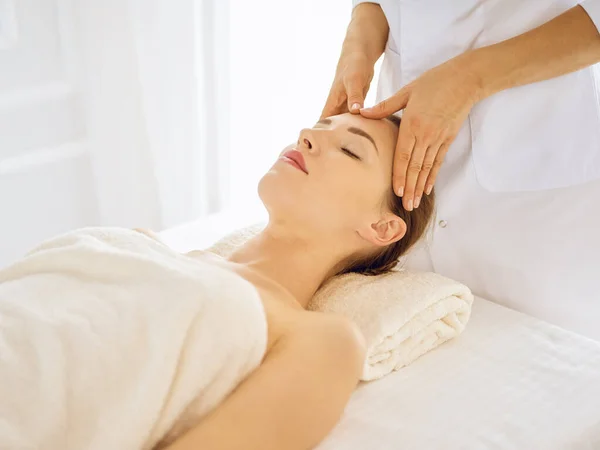 Красива жінка насолоджується масажем обличчя із закритими очима — стокове фото