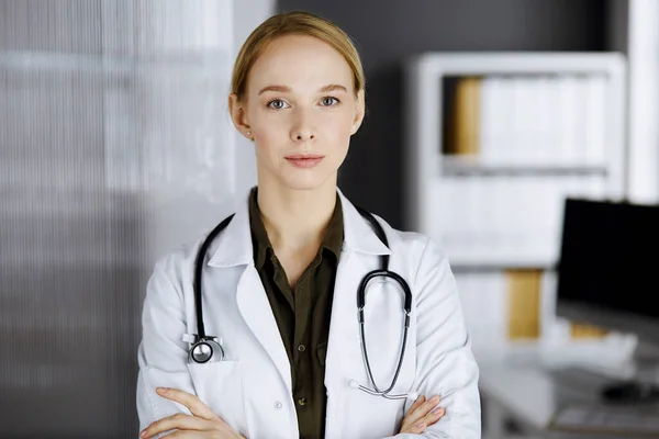 Amichevole dottoressa sorridente in piedi in clinica. Ritratto di donna medico amichevole. Servizio medico perfetto in ospedale. Concetto di medicina — Foto Stock