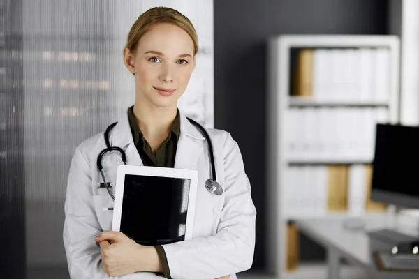 Amichevole medico femminile sorridente utilizzando tablet computer in clinica. Servizio medico perfetto in ospedale. Concetto di medicina — Foto Stock