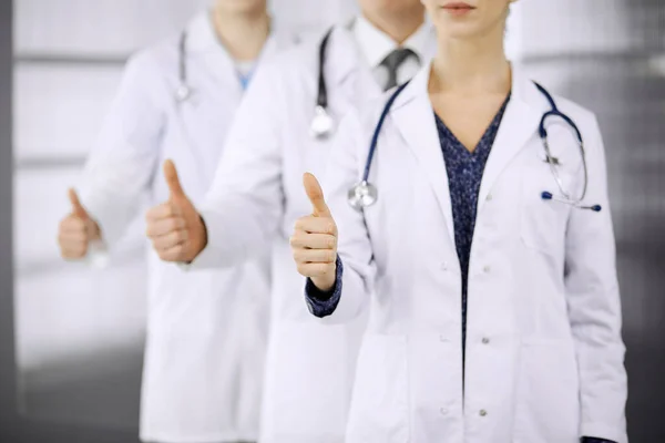 Médicos em pé como uma equipe com os polegares para cima na clínica e pronto para ajudar os pacientes. Conceito de assistência médica, seguro e medicina — Fotografia de Stock