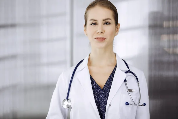 Allegro dottore donna in piedi in clinica. Ritratto di amichevole sorridente medico donna. Servizio medico perfetto in ospedale. Concetto di medicina — Foto Stock