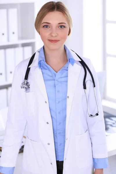 Mladá doktorka v nemocnici, dívá se na kameru. Modrá blůza terapeuta vypadá dobře. Medicína a koncept zdravotní péče — Stock fotografie