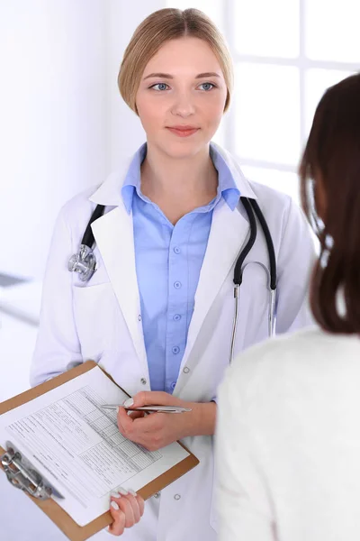 Νεαρή γυναίκα γιατρός και ασθενής στην ιατρική εξέταση στο γραφείο του νοσοκομείου. Μπλε χρώμα μπλούζα του θεραπευτή φαίνεται καλό. Ιατρική και υγειονομική περίθαλψη έννοια — Φωτογραφία Αρχείου