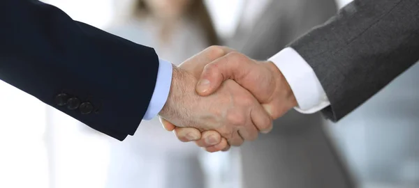 Business people shaking hands while standing with colleagues after meeting or negotiation, close-up. Group of unknown businessmen and women in modern office. Teamwork, partnership and handshake — Stock Photo, Image