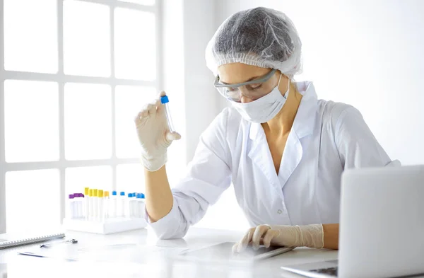 Científica profesional en gafas protectoras investigando tubo con reactivos en laboratorio. Conceptos de medicina e investigación — Foto de Stock