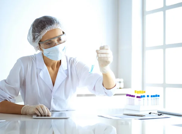 Professionelle Wissenschaftlerin mit Schutzbrille, die Röhre mit Reagenzien im Labor untersucht. Konzepte von Medizin und Forschung — Stockfoto