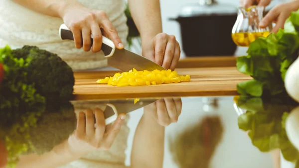 Fechar-se de mãos humanas que cozinham na cozinha. Mãe e filha ou duas amigas cortando legumes para salada fresca. Conceitos de amizade, jantar de família e estilo de vida — Fotografia de Stock