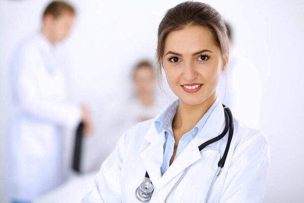 Female doctor smiling on the background with patient in the bed and two doctors