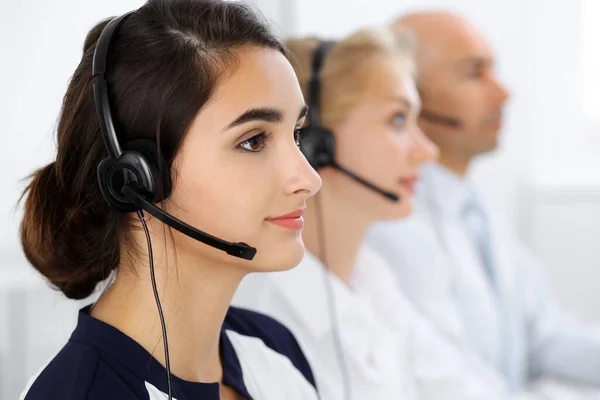 Operatori di call center al lavoro. Concentrarsi sulla bella donna americana latina in cuffia — Foto Stock