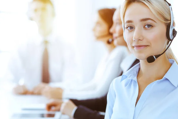 Grupo de operadores telefónicos diversos en el trabajo en la oficina soleada. Mujer de negocios guapo con auriculares clientes de consulta. Centro de llamadas y concepto de gente de negocios —  Fotos de Stock