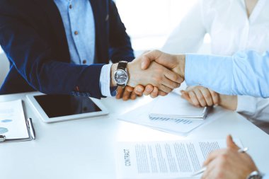 İş adamları toplantıda ya da pazarlıkta el sıkışıyor, yakın plan. Modern ofisteki bir grup tanınmamış iş adamı ve kadın. Takım çalışması, ortaklık ve tokalaşma konsepti, tonlu resim