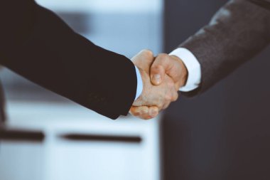 İş adamları toplantıdan ya da pazarlıktan sonra iş arkadaşlarıyla el sıkışıyorlar. Yakın plan. Modern ofisteki bir grup tanınmamış iş adamı ve kadın. Takım çalışması, ortaklık ve tokalaşma