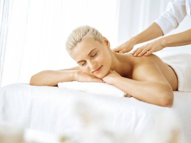 Güzel sarışın kadın kapalı gözlerle sırt masajından hoşlanıyor. Spa salonu konsepti