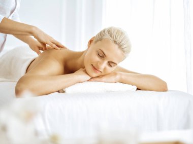 Güzel sarışın kadın kapalı gözlerle sırt masajından hoşlanıyor. Spa salonu konsepti
