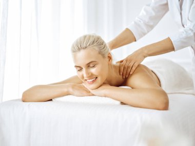 Güzel sarışın kadın kapalı gözlerle sırt masajından hoşlanıyor. Spa salonu konsepti