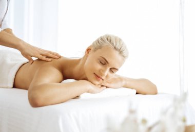 Güzel sarışın kadın kapalı gözlerle sırt masajından hoşlanıyor. Spa salonu konsepti