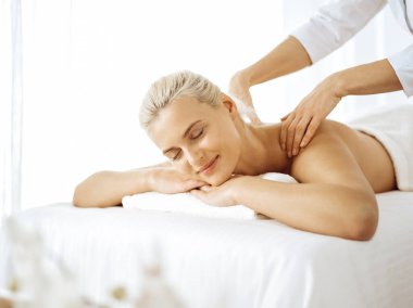 Güzel sarışın kadın kapalı gözlerle sırt masajından hoşlanıyor. Spa salonu konsepti