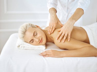 Güzel sarışın kadın kapalı gözlerle sırt masajından hoşlanıyor. Spa salonu konsepti