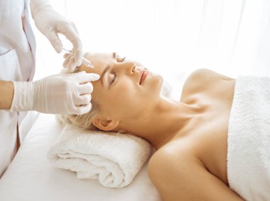 Güzellik uzmanı elleri şırıngayla kadın yüzüne güzellik prosedürü uyguluyor. Kozmetik tıp ve cerrahi, güzellik enjeksiyonları konsepti