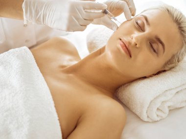 Güzellik uzmanı elleri şırıngayla kadın yüzüne güzellik prosedürü uyguluyor. Kozmetik tıp ve cerrahi, güzellik enjeksiyonları konsepti