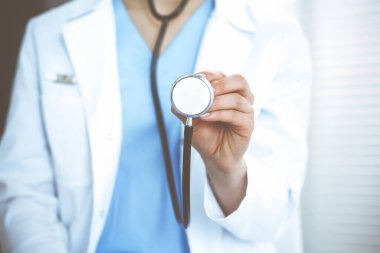 Bilinmeyen doktor kadın steteskop başı tutuyor, yakın plan. Doktor hastayı muayene etmeye ve yardım etmeye hazır. Sağlık hizmetleri, en iyi tedavi ve tıp konseptinde yardım ve sigorta