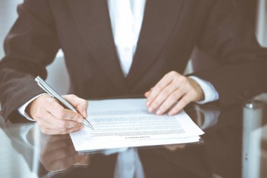 Sözleşme belgesini kalemle teslim eden kimliği belirsiz kadın elleri. Anlaşma imzalama veya iş konsepti