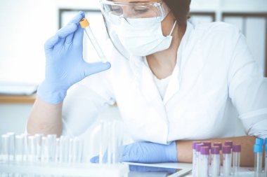 Koruyucu gözlüklü profesyonel kadın bilim adamının laboratuarda reaktörlerle deney yapması. Tıp ve araştırma konsepti