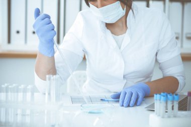 Koruyucu gözlüklü profesyonel kadın bilim adamının laboratuarda reaktörlerle deney yapması. Tıp ve araştırma konsepti