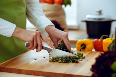 Mutfakta pişen bilinmeyen insan elleri. Kadın sebze salatasıyla meşgul. Sağlıklı yemek ve vejetaryen gıda konsepti.