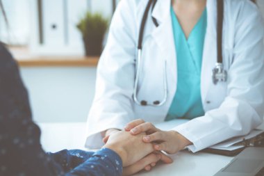 Doktorun kadın hastasına güvence verdiği yakın plan. Tıbbi etik ve güven kavramı