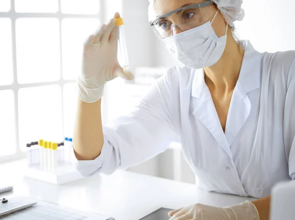 Científica profesional en gafas protectoras investigando tubo con reactivos en laboratorio. Conceptos de medicina e investigación — Foto de Stock