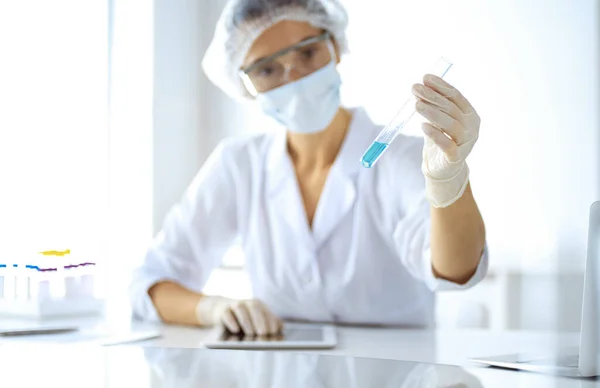 Professionelle Wissenschaftlerin mit Schutzbrille, die Röhre mit Reagenzien im Labor untersucht. Konzepte von Medizin und Forschung — Stockfoto