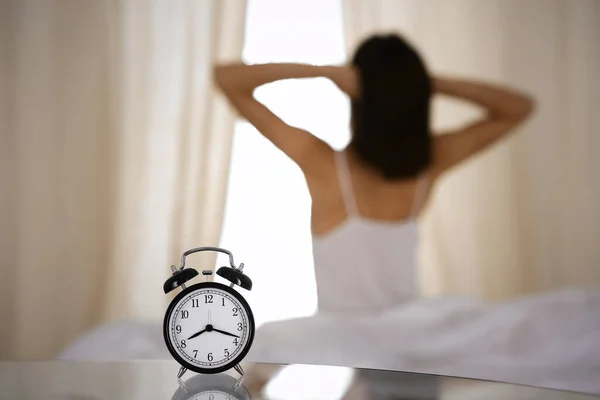 Femme étirant les mains au lit après le réveil, éruption de soleil. Brunette entrant dans une journée heureuse et détendue après une bonne nuit de sommeil et vue arrière. Concept d'une nouvelle journée et d'un week-end joyeux — Photo