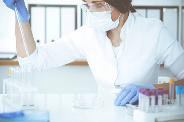 Close-up de cientista profissional feminino em óculos de proteção fazendo experiência com reagentes em laboratório. Medicina e conceito de pesquisa — Fotografia de Stock