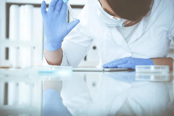 Close-up de cientista profissional feminino em óculos de proteção fazendo experiência com reagentes em laboratório. Medicina e conceito de pesquisa — Fotografia de Stock