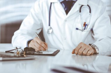 Bilinmeyen erkek doktor, klinikteki ilaç geçmişi kayıtlarıyla birlikte yakın planda oturuyor. İşteki genç doktor. Mükemmel sağlık hizmeti, tıp konsepti
