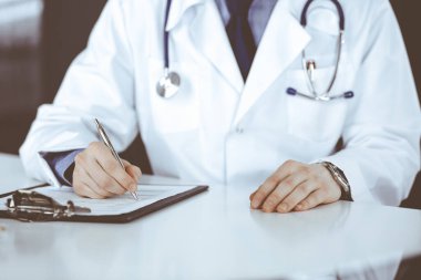 Bilinmeyen erkek doktor, klinikteki ilaç geçmişi kayıtlarıyla birlikte yakın planda oturuyor. İşteki genç doktor. Mükemmel sağlık hizmeti, tıp konsepti