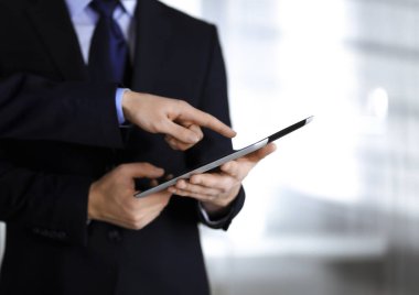 Modern bir ofiste çalışırken, iş adamları tablet bilgisayar kullanıyorlar. İş yerinde iş arkadaşı olan tanınmamış bir iş adamı ya da erkek girişimci. Takım çalışması ve ortaklık kavramı