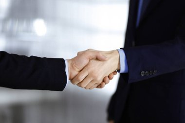 İş adamları el sıkışıyor, yakın plan. Modern bir ofiste duran bir grup tanınmamış iş adamı. Takım çalışması, ortaklık ve el sıkışma kavramı