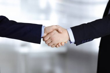 İş adamları el sıkışıyor, yakın plan. Modern bir ofiste duran bir grup tanınmamış iş adamı. Takım çalışması, ortaklık ve el sıkışma kavramı